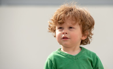 portrait of young boy with green sweater playing outdoors