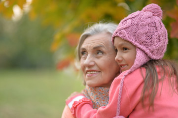 Portrait of grandmother and granddaughter in autumnal park