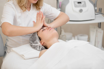 Woman beautician makes a professional massage to a young girl. Beauty treatments for skin care in...