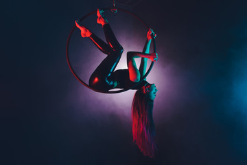 Aerial acrobat in the ring. A young girl performs the acrobatic elements in the air ring.