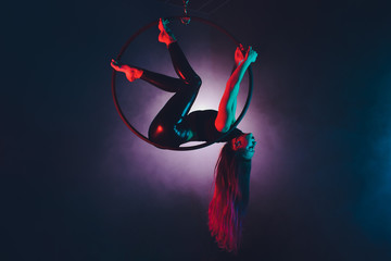 Aerial acrobat in the ring. A young girl performs the acrobatic elements in the air ring.