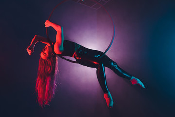 Aerial acrobat in the ring. A young girl performs the acrobatic elements in the air ring.