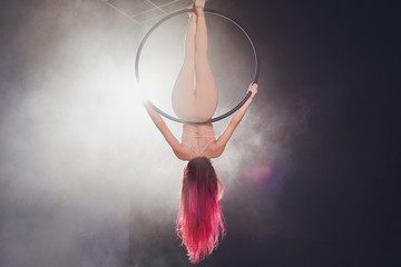 Aerial acrobat in the ring. A young girl performs the acrobatic elements in the air ring.