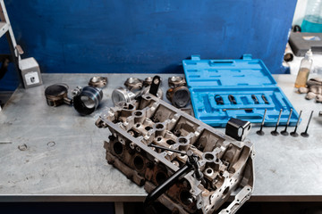 Obraz na płótnie Canvas Disassembled engine block is on the table. the mechanic opened the locking valve mechanism. Motor capital repair. Sixteen valves and four cylinder. Car service concept.