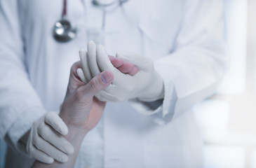 Medical doctor wearing latex gloves holding patient’s hand to give support in hospital setting