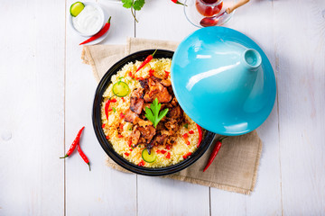 Tajin with couscous, vegetables and meat on white background