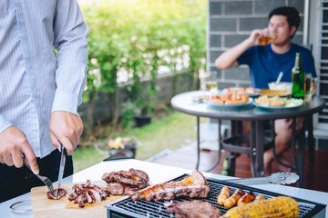 Group of friends Two young man enjoying grilled meat and raise a glass of beer to celebrate the holiday festival happy drinking beer outdoors and enjoyment at home