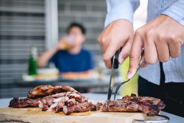 Group of friends Two young man enjoying grilled meat and raise a glass of beer to celebrate the holiday festival happy drinking beer outdoors and enjoyment at home