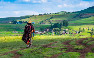 Basotho man with basotho blanket and basotho hat walking in the mountains in Semonkong, Lesotho, Southern Africa - obrazy, fototapety, plakaty