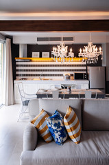 Light tone sofa couch and colourful pillows in living room with dining area