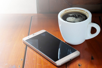 Photo of smartphone and black coffee on wood table with space for write wording, innovation that change the world such as communication way, business strategies, marketing strategies