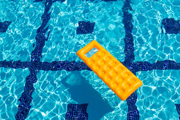 Orange inflatable mattress in the pool.