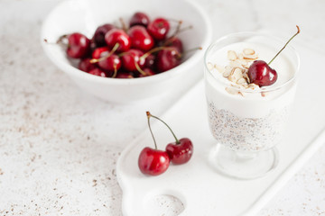 yogurt with chia seeds, oatmeal and cherries on a light background