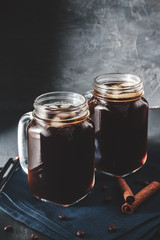 Coffee with ice in a glass mason jars on the napkin at dark background