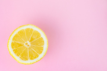yellow sliced lemon on a pastel pink monochromatic background