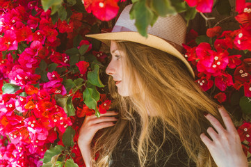 Naklejka premium Portrait of smiling girl in black dress among purple bougainvillaea