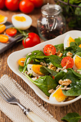 Delicious salad of fresh spinach, boiled egg, tomatoes, nuts and sunflower seeds