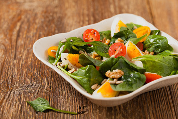 Delicious salad of fresh spinach, boiled egg, tomatoes, nuts and sunflower seeds