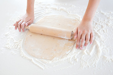 top view of a child making pizza dough on a light tabletop