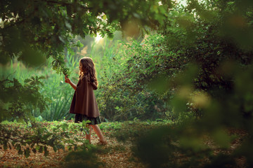 Girl in a cape with a basket walking in a forest