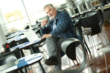 Senior man at public place connected on laptop computer