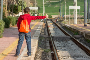 Obraz na płótnie Canvas Young hitchhiker waiting of the train, standing on railway