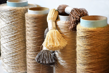 Row of large bobbins of polyethylene thread. Coils of warm beige and pastel tones with a closeup,...