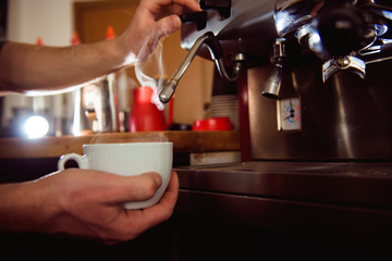Details of barista preparing fresh espresso on industrial brewing machinery.