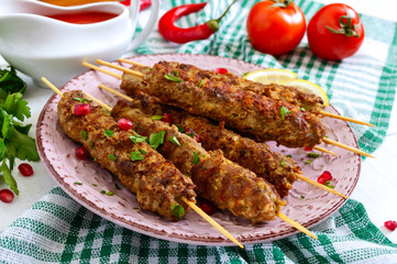 Tasty lula kebab on the plate on a white wooden table. Chopped meat on wooden skewers, grilled. Eastern cuisine.