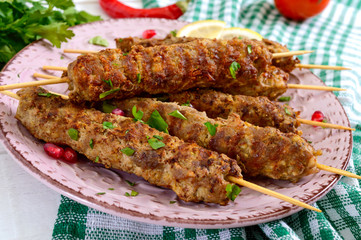 Tasty lula kebab on the plate on a white wooden table. Chopped meat on wooden skewers, grilled. Eastern cuisine.