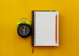 Blank white notepad with pencil and alarm clock isolated on yellow background. - 260956462