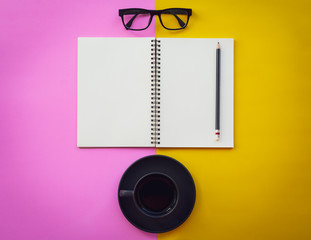 Blank white notepad with black coffee cup, pencil and glasses on two tone pink and yellow background. - 260956636