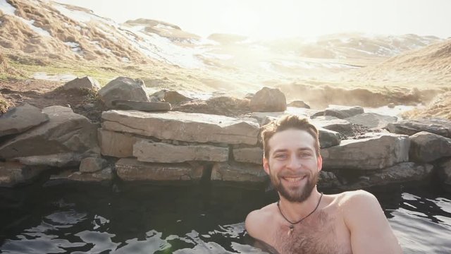 Happy man relax in geothermal hot pool in Iceland