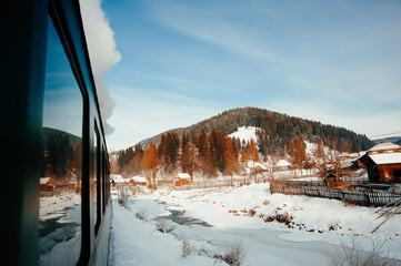 Photo taken from the train, winter landscape with hill, trees and house