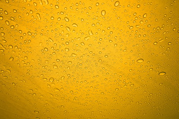Rain drops on the solid abstract yellow background. Bright shiny pattern of raindrops