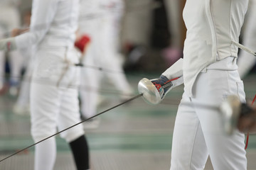 Young people fencers standing in the hall on a fencing tournament. No face shown
