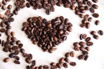 a handful of coffee beans in the shape of a heart, after roasting on the table
