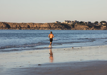 Man is running  along the beach in Saint-Malo, Brittany, France
