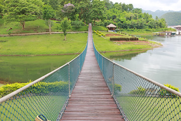 Wooden rope suspension bridge for walk crossing river.
