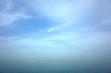 Blue seascape of Gulf of Oman seen from Arabian peninsula with yellow line of sandstorm over Iran