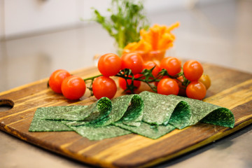 Girl chef slicing vegetables. Tomatoes, parsley, onion, apple. Wooden board for slicing vegetables.Curtain processes