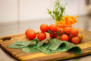 Girl chef slicing vegetables. Tomatoes, parsley, onion, apple. Wooden board for slicing vegetables.Curtain processes