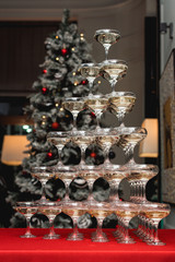 Fototapeta na wymiar Champagne tower on a red table with Christmas tree in the background