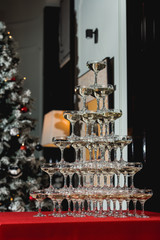 Champagne tower on a red table with Christmas tree in the background