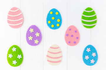 Closeup top view photo of cute diy colorful pastel eggs decorated with dots, stripes and flowers isolated on white painted wooden background. Happy Easter holiday greeting card. Horizontal image.