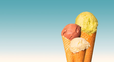 Scoops of ice cream on blue background. Sweet dessert in wafer cones. Natural ice cream with chocolate, pistachio and vanilla or cream flavor. Free copy space. Floating frame.