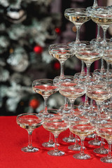 Champagne tower on a red table with Christmas tree in the background