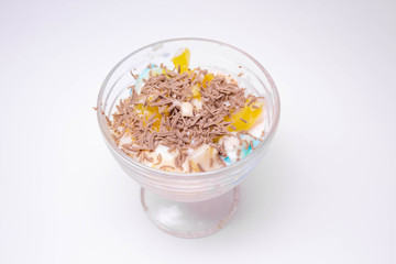 tasty homemade dessert in a sundae with colorful ice cream, fruit, chocolate chips on a white background for children and adults.