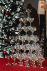 Champagne tower on a red table with Christmas tree in the background