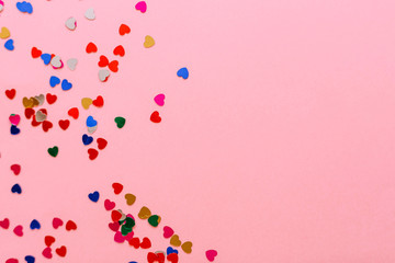 Multicolored hearts on a pink background. Place for inscription.